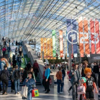Impression der Glashalle mit vielen Besucher:innen und bunten Fahnen auf der Buchmesse 2025 Impression der Glashalle mit vielen Besucher:innen und bunten Fahnen auf der Buchmesse 2025