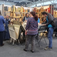 Leipziger Antiquariatsmesse: Besucher:innen stöbern in Antiquariaten vor gefüllten Bücherregalen Leipziger Antiquariatsmesse: Besucher:innen stöbern in Antiquariaten vor gefüllten Bücherregalen