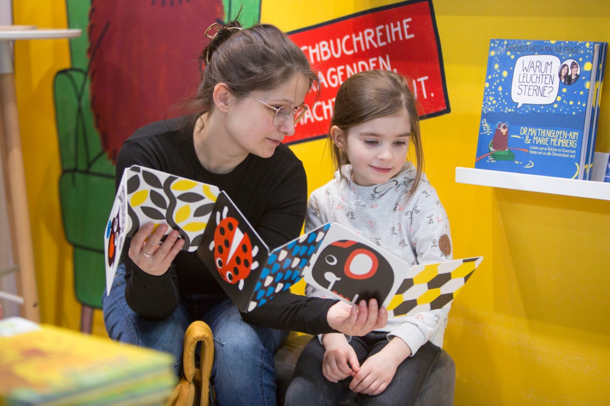 Frau und Mädchen lesen gemeinsam ein Bilderbuch auf der Leipziger Buchmesse 2024 Frau und Mädchen lesen gemeinsam ein Bilderbuch auf der Leipziger Buchmesse 2024
