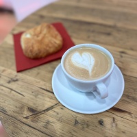 Kaffeetasse und Croissant auf einem Holztisch in der buchbar während der Leipziger Buchmesse 2024 Kaffeetasse und Croissant auf einem Holztisch in der buchbar während der Leipziger Buchmesse 2024