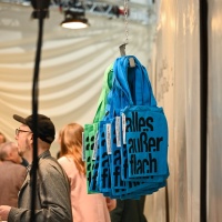 Bedruckte Jutebeutel in blau und grün am Messestand des Gastlandes Niederlande & Flandern auf der Leipziger Buchmesse 2024 Bedruckte Jutebeutel in blau und grün am Messestand des Gastlandes Niederlande & Flandern auf der Leipziger Buchmesse 2024