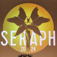 Die 3 Preisstatuen vom Seraph 2024 stehen auf der Bühne, im Hintergrund wird das Logo vom Seraph auf einer großen Leinwand gezeigt