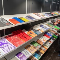 Langes Bücherregal mit verschiedenen Büchern aus dem Druckkunsbereich auf der Leipziger Buchmesse 2024 Langes Bücherregal mit verschiedenen Büchern aus dem Druckkunsbereich auf der Leipziger Buchmesse 2024