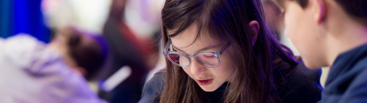 2 kleine Kinder sitzen an einem Tisch und betrachten interessiert ein Objekt darauf während der Leipziger Buchmesse 2025