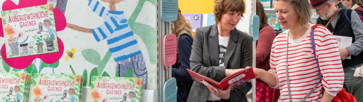 Zwei Frauen unterhalten sich über ein Kinderbuch auf der Leipziger Buchmesse 2025