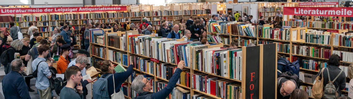 Leipziger Antiquariatsmesse auf der Leipziger Buchmesse 2025 mit Besucherinnen vor Bücherregalen