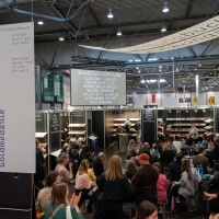 Der Buchkunst-Messebereich auf der Leipziger Buchmesse 2025 mit Besucherinnen vor Bücherregalen Der Buchkunst-Messebereich auf der Leipziger Buchmesse 2025 mit Besucherinnen vor Bücherregalen