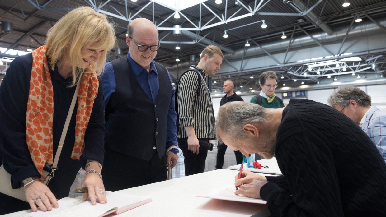 Autor signiert ein Buch für erfreute Fans an einem Signiertisch im Signierbereich der Leipziger Buchmesse 2025