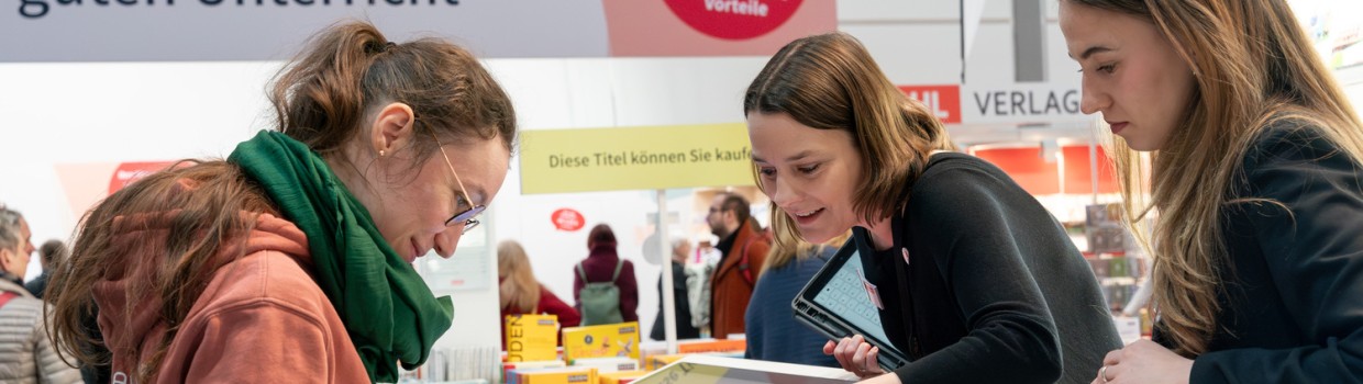 Messestand im Bereich Bildung auf der Leipziger Buchmesse 2026 mit 3 interessierten Besucherinnen