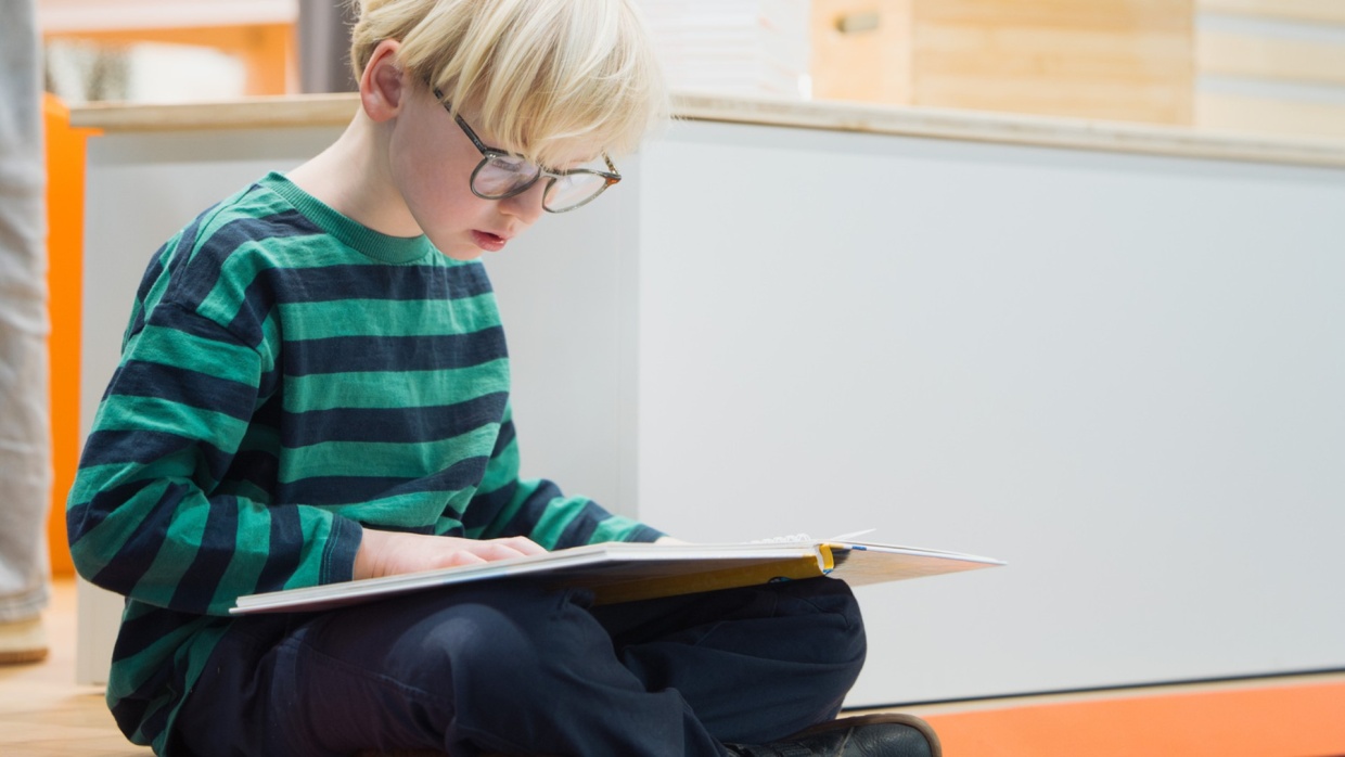 kleiner Junge mit Brille liest ein Bilderbuch auf der Leipziger Buchmesse 2026