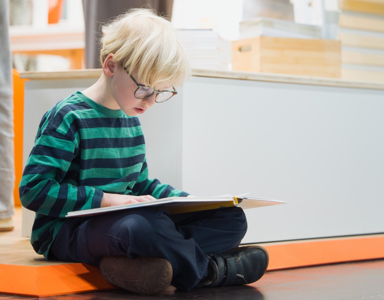 kleiner Junge mit Brille liest ein Bilderbuch auf der Leipziger Buchmesse 2026