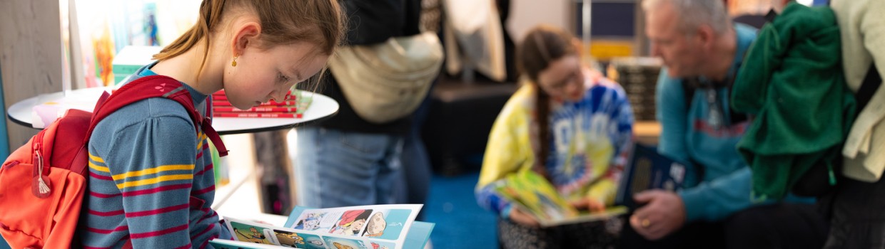 junges Mädchen liest ein Comicbuch auf der Leipziger Buchmesse 2026