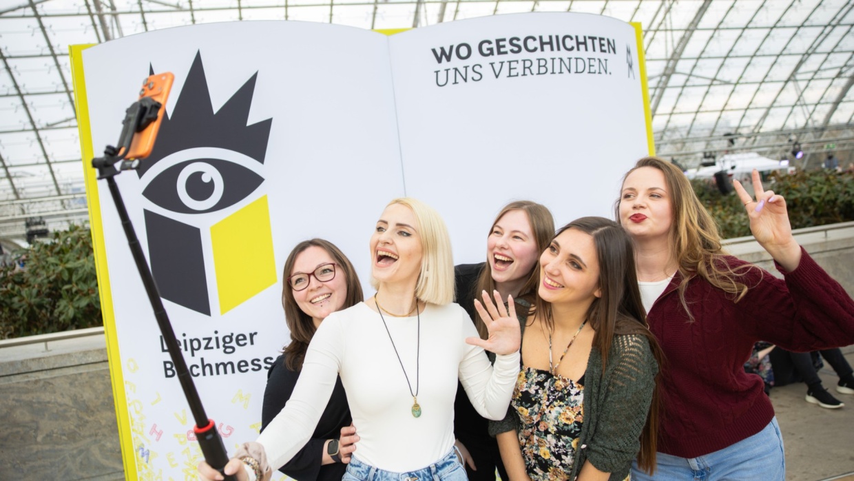 Fünf junge Besucherinnen machen ein Selfie vor der Buchmesse-Fotowand auf der Leipziger Buchmesse 2026
