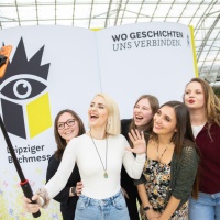 Fünf junge Besucherinnen machen ein Selfie vor der Buchmesse-Fotowand auf der Leipziger Buchmesse 2026