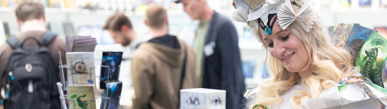 kostümierte Person liest ein Buch im Phantastikbereich auf der Leipziger Buchmesse 2026