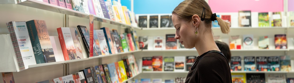 Besucherin blättert in Büchern am Finnland- und Norwegen-Stand der Leipziger Buchmesse 2026