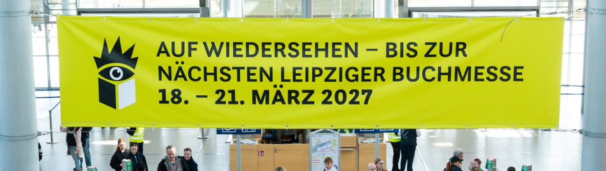 Gelbes Banner zur Leipziger Buchmesse 2027 hängt über Besuchenden in derEingangshalle