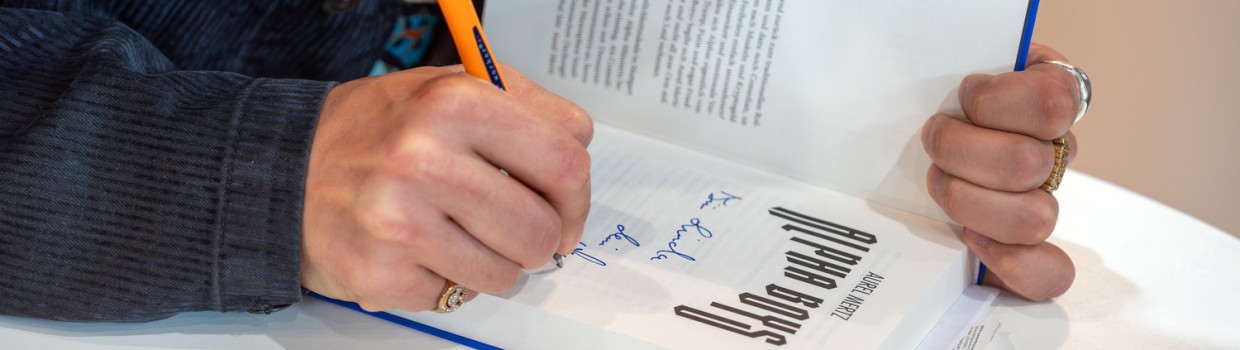 Nahaufnahme der Signatur von Autor Aurel Mertz in einem aufgeschlagenen Buch auf der Leipziger Buchmesse 2026