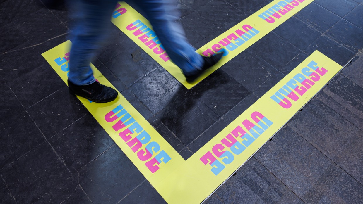 Foto vom Hallenboden der Leipziger Buchmesse mit gelben UVERSE-Aufklebern in Pfeilform 