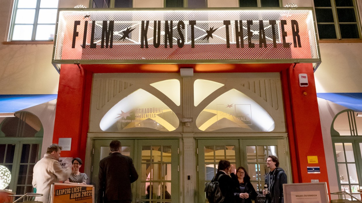Der Eingang der Schaubühne Lindenfels. Die Türen sind mit einer roten Baustruktur umrahmt. Darüber steht "Film Kunst Theater". Über dem Gebäude steht eine große Uhr. 