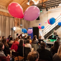 Leipzig Reads event with stage talk in front of a packed audience in a large room decorated with balloons and fairy lights during the Leipzig Book Fair 2024