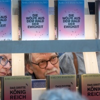 A woman and a man look through a bookshelf at the 2025 Book Fair.