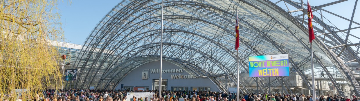 Impression of the 2025 Book Fair with many visitors in front of the main entrance to the Glass Hall