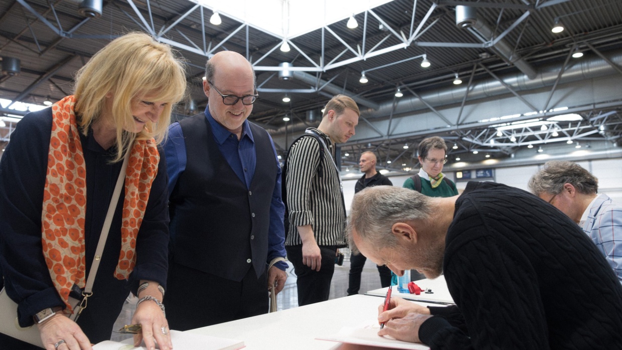 Author signs a book for delighted fans at a signing table in the signing area of the Leipzig Book Fair 2025.