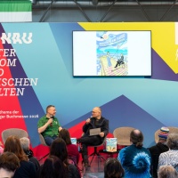 Stephan Ozsváth and Christian Schmiedbauer talking on stage at the trade fair stand of the Focus Topic Danube at Leipzig Book Fair 2026