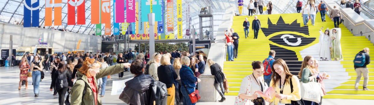 A bustling glass hall during Leipzig Book Fair, filled with cheerful visitors