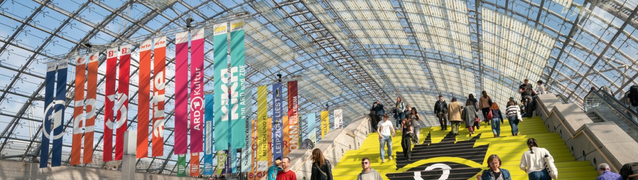 A bustling glass hall during Leipzig Book Fair, filled with cheerful visitors