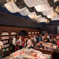 Visitors browse a decorated book stand beneath chandeliers at Leipzig Book Fair 2026